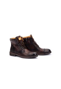Botas de tobillo de cuero marrón con cordones y una cremallera lateral. Presentan una puntera redonda, una parte superior texturizada, forro naranja y costuras en contraste.