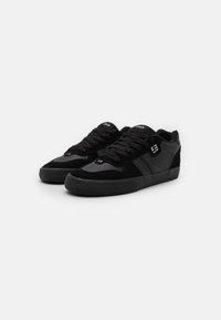 Zapatillas negras con una mezcla de ante y materiales texturizados. Presentan acentos perforados, cordones planos y una suela de goma. Diseño sencillo.