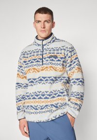 Φλις πουλόβερ με μισό φερμουάρ, χαρακτηριστικό σχέδιο σε μπλε, πορτοκαλί και κρέμα. Μαλακή υφή με γιακά και λογότυπο.