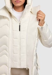 Jachetă puffer albă cu un design texturat, matlasat. Prezintă un fermoar frontal, o glugă cu șnur și buzunare laterale. Textură de material neted.