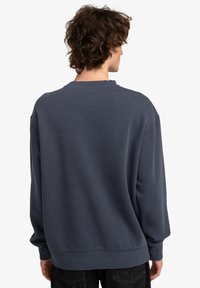 Felpa blu navy dalla vestibilità comoda, con collo a girocollo a costine e maniche lunghe. Tessuto morbido con un colore uniforme, senza motivi o dettagli visibili.
