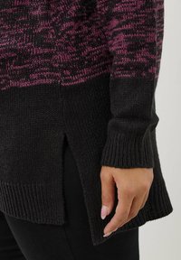 Sweter dzianinowy w kolorze czarnym z gradientowym różowym wzorem na górze. Posiada prążkowane mankiety oraz boczne rozcięcie na dole dla dodatkowego akcentu.