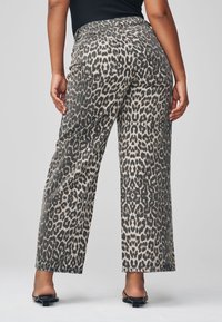 Pantalon à jambes larges imprimé léopard en mélange de coton. Comprend deux poches arrière et une taille haute. Sandales noires à brides complètent le look.