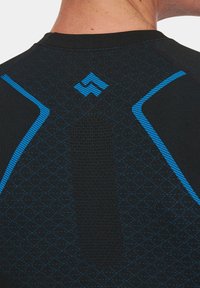 Czarna koszulka sportowa z niebieskimi akcentami, z geometrycznym wzorem i teksturowanym centralnym panelem. Projekt obejmuje ukośne paski i szczegóły logo.