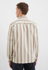 Gestreepte blouse met lange mouwen, voorzien van lichtbruine en crèmekleurige verticale strepen, groene accenten, knopenmanchetten en een klassiek kraagontwerp.