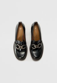 Mocassins en cuir noir avec un bout arrondi, dotés d'un accent de chaîne en argent sur le devant et d'une semelle texturée marron. Taille 37.