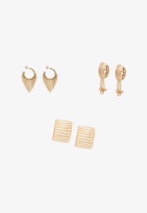 Három pár aranyszínű fülbevaló: bojtos karika, gyöngyökkel díszített gravírozott karika és texturált négyzet alakú bedugós fülbevaló fehér háttéren.