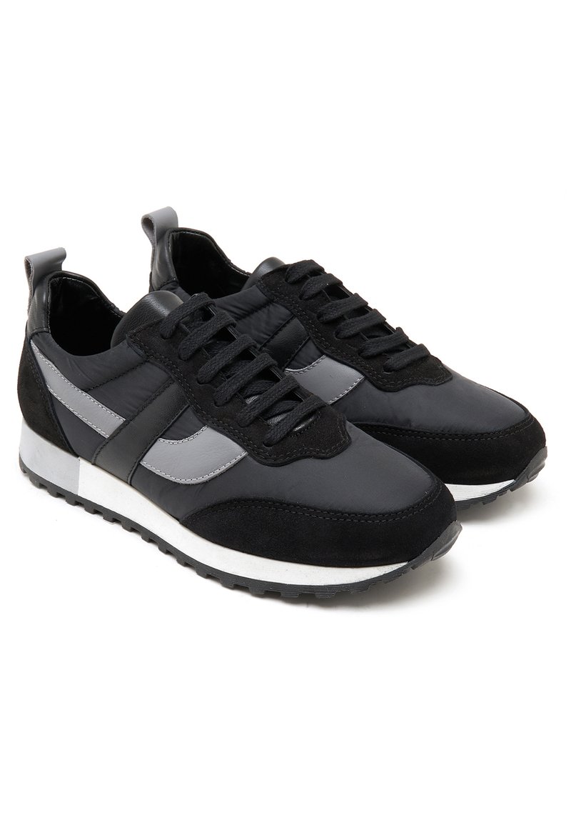Schwarze Sportschuhe aus einer Mischung aus glattem Leder und Wildleder. Sie haben eine strukturierte Oberfläche, graue Akzente und eine weiße Außensohle.