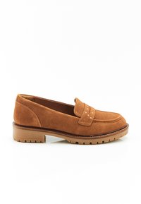 Mocassins en daim beige avec un bout arrondi, des coutures décoratives et une semelle en caoutchouc dotée de rainures de traction pour une bonne adhérence.