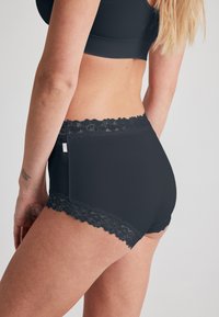 Czarne majtki o wysokim stanie, z koronkowym wykończeniem przy brzegach oraz gładką teksturą materiału.