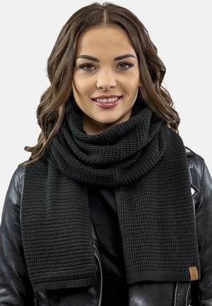 Černý pletený šátek s texturovaným žebrovaným vzorem, volně obtočený kolem krku. Na konci se nachází malá značka.