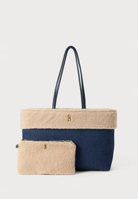 Tote bag din denim albastru cu un capac din blană sintetică bej, având două mânere și un mic pouch asortat cu un accent logo auriu.