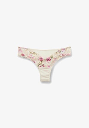 String beige en dentelle florale rose le long de la ceinture et du panneau avant, posé à plat sur un fond blanc.