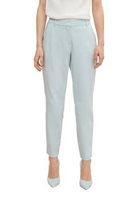 Pantalon ajusté bleu clair en tissu lisse, à coupe slim, avec poches avant et taille mi-haute, assorti à des talons du même ton.