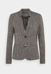 Harmaa teksturoidulla pinnalla varustettu bleiseri, jossa on lovikaulus, kaksi etutaskua ja yksirivinen napitus. Sisäpuoli vuorattu mustalla satiinilla kontrastia varten.