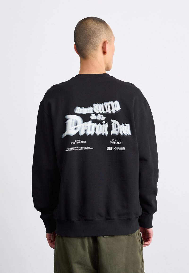 Sweatshirt negru cu guler rotund, prezentând text grafic alb pe spate cu un efect de estompare, manșete și tiv cu ripstop, fabricat dintr-un material moale.