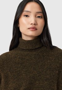 Maglione lavorato a maglia di un verde scuro con colletto alto, realizzato in un tessuto morbido e testurizzato simile alla lana. Design minimalista senza motivi o dettagli visibili.
