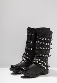 Czarne skórzane botki sięgające kostki z wieloma poziomymi paskami oraz okrągłymi metalowymi ćwiekami, zaokrąglony czubek oraz niski, zdobiony obcas.