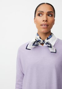 Maglione lilla con maniche lunghe e una vestibilità rilassata, accentuato da un foulard di seta decorato in bianco, blu e verde annodato attorno al collo.