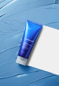 Blaue Tube der Medicube Zero Pore Blackhead Mud Mask mit silberner Schrift und klarem Verschluss, platziert auf einem strukturierten blauen Hintergrund.