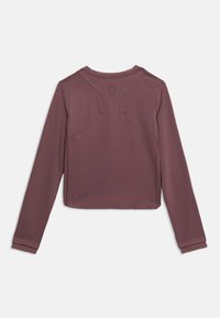 Τοπ με μακριά μανίκια σε βαθύ μωβ χρώμα. Λείο, ελαστικό ύφασμα με ραφές στους ώμους και λεπτομέρεια με λογότυπο στο πίσω μέρος. Χαλαρή εφαρμογή.