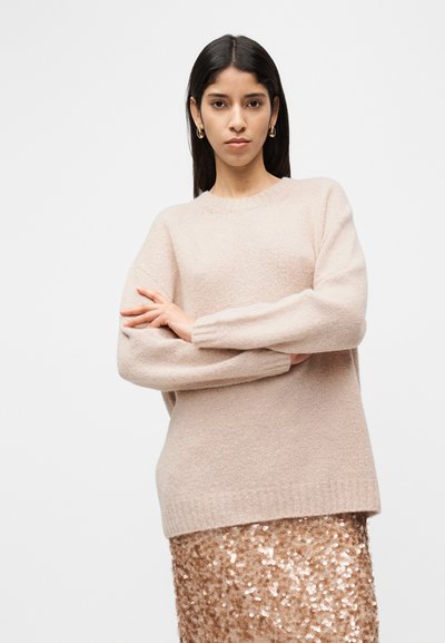 Ροζ ανοιχτό ροζ πλεκτό πουλόβερ με στρογγυλή λαιμόκοψη και μακριά μανίκια, με μαλακή υφή, συνδυασμένο με φούστα από παγιέτες σε ροζ χρυσό με λάμψη.