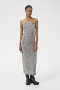 Vestido de denim cinza sem alças com costuras verticais e detalhes decorativos, silhueta ajustada e bainha longa e reta, combinado com botas pretas até ao tornozelo.