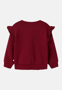 Sudadera burdeos con acentos con volantes en los hombros, confeccionada con tela texturizada, con un dobladillo y cuello de canalé.