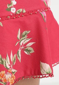 Rode bloemenrok met groene bladeren en oranje bloemen. Heeft een textuurzoom met een kanten rand en kleine kralen langs de rand.