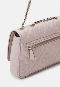 Sac à main matelassé rose clair avec fermeture éclair dorée et bandoulière chaîne, présentant un motif monogrammé cousu sur un cuir souple.