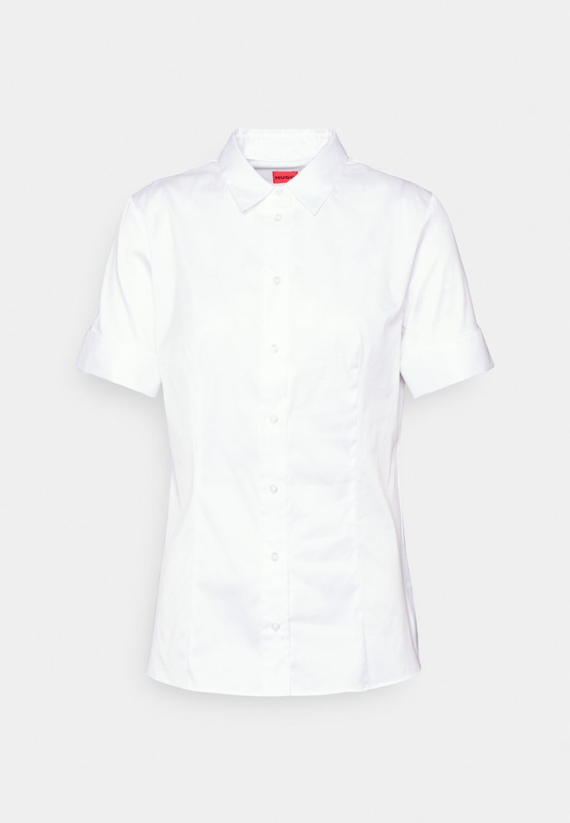 Chemise blanche à manches courtes avec un bouton, confectionnée en tissu lisse. Présente un col pointu, une coupe droite et des coutures latérales discrètes pour un look ajusté.