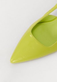 Chaussure à bout pointu en brillant cuir vert lime, avec un design découpé, dotée d'une doublure intérieure lisse et d'un talon élégant.