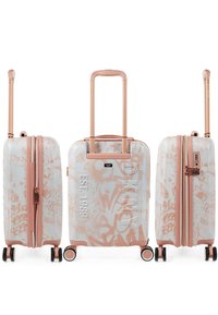 Maleta rígida blanca con patrones de graffiti en rosa. Cuenta con ruedas dobles, un mango telescópico y compartimentos con cremallera.