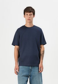 Navyblaue Baumwoll-T-Shirt mit kurzen Ärmeln und rundem Halsausschnitt, mit einem lockeren Schnitt und glatter Textur.