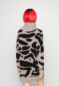 Abito a maglia a maniche lunghe in morbido materiale grigio, con un motivo astratto nero. Collo alto e vestibilità ampia, con orlo a metà coscia.