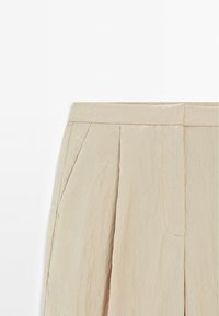 Beige geplooide shorts van lichtgewicht stof, met zijzakken, een gladde tailleband en een zachte, gekreukelde textuur.