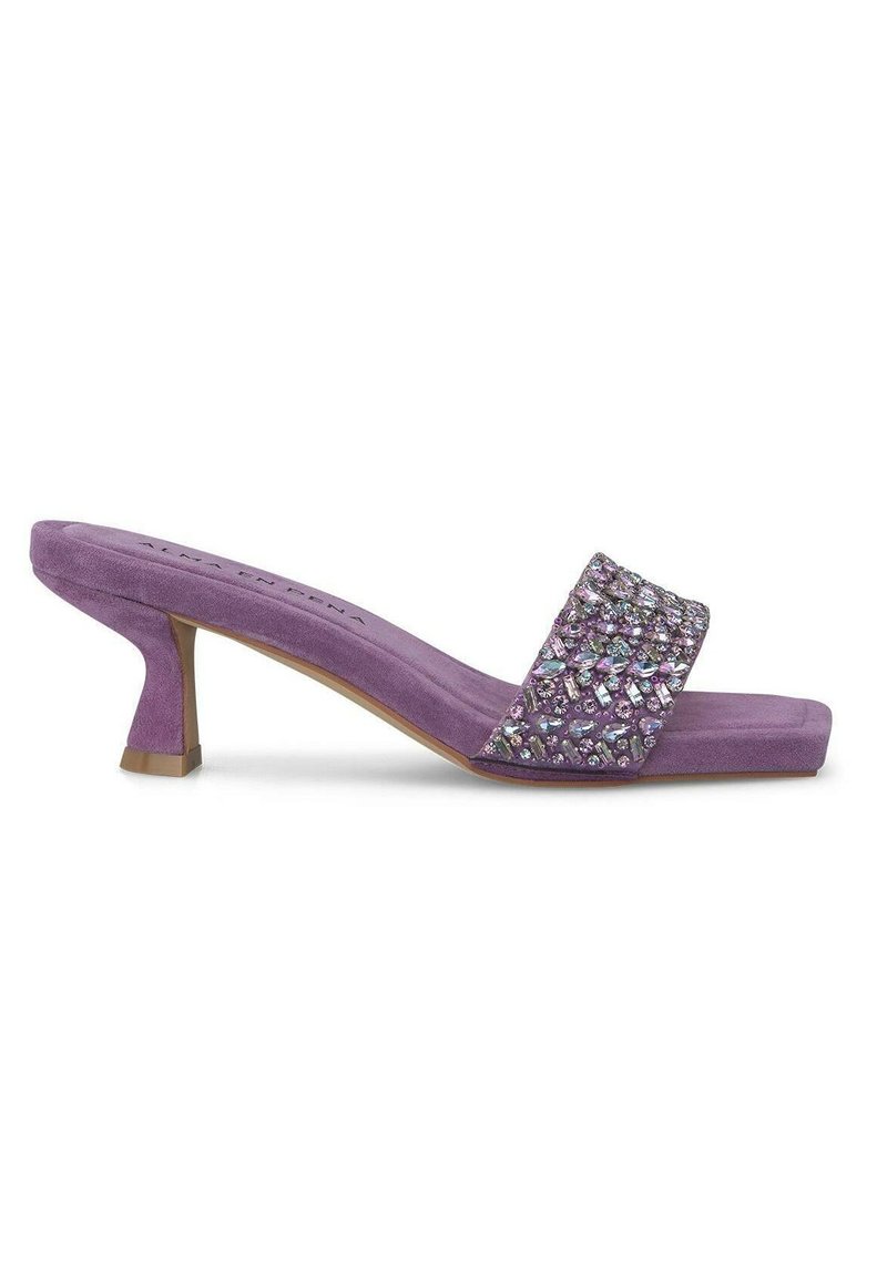 Mule in suede viola con tacco alto, dotate di una larga fascia decorata con strass e punta rettangolare. Tacco basso a blocco, texture morbida.