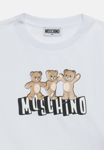 Λευκό παιδικό μπλουζάκι με τρεις καφέ αρκουδάκια πάνω από το έντονο κείμενο «MOSCHINO» σε μαύρα και λευκά γράμματα μπλοκ.