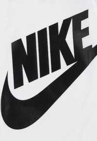 Tecido branco com um grande logótipo preto da Nike com um design de swoosh, apresentando uma textura suave e uma tipografia ousada.