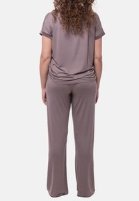 Ljusbrun fritidsklädset som består av en lös passform med kortärmad topp och matchande byxor, tillverkade av mjukt tyg med en slät textur.