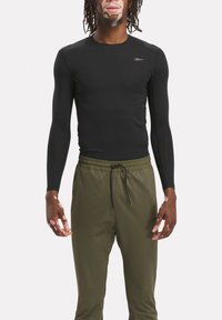 Black long-sleeve athletic shirt with a fitted design, paired with green elastic-waist joggers. Material appears smooth and stretchy.