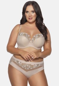Beige lingeriesæt bestående af en bh med blomsterlacemønster og underwire, parret med matchende trusser, der har laceindsatser og glat stof.