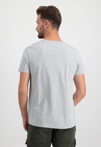 Hellgraues T-Shirt mit kurzen Ärmeln, runder Ausschnitt und weichem Material; getragen mit olivgrünen Cargo-Shorts; schlichte Rückansicht.