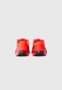 Red athletic shoes with a textured finish, cushioned heel, and black outsole. Features "METCON" branding on the heel.