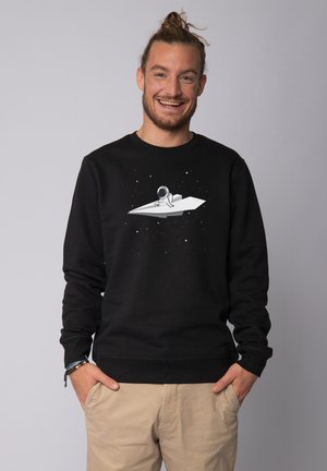 Black sweatshirt featuring a central graphic of an astronaut on a paper plane against a starry background. Ribbed cuffs and hem.