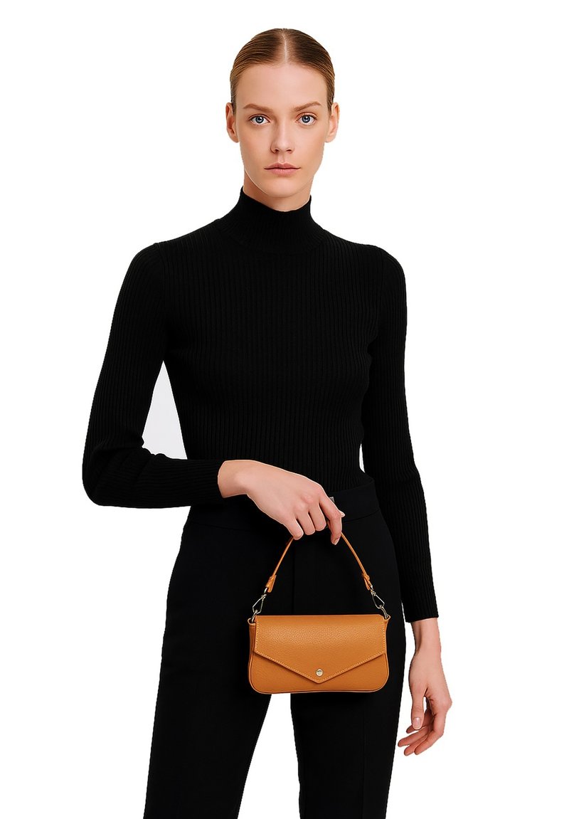 Borsa a mano in pelle color cuoio con finitura testurizzata, design sottile, pattina pieghevole e manico corto. Il modello indossa un dolcevita nero a coste.