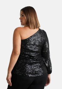 Top nero con paillettes, caratterizzato da una spalla scoperta e una lunga manica a sbuffo. Tessuto texturizzato con una finitura lucida, che crea un aspetto glamour.