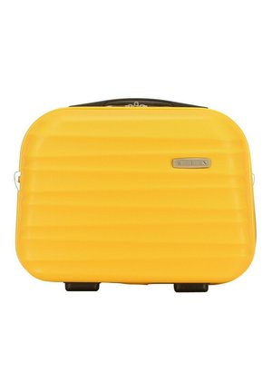 Yellow hard-shell suitcase with a ribbed texture, black accents, a top handle, and two wheels. Features a brand logo plate on the front.