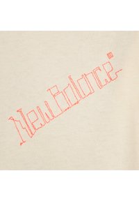 Beiger Stoff weist den in pinkem Garn gestickten Text "New Balance" auf, mit einem einfachen Design in Blockbuchstaben.