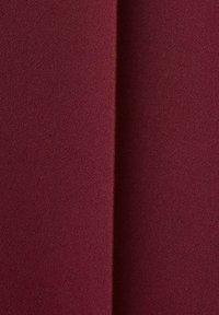 Burgundska tkanina z dodelano, teksturirano površino, z drapiranimi področji in subtilnimi gubami. Material izgleda mehak in lahek.